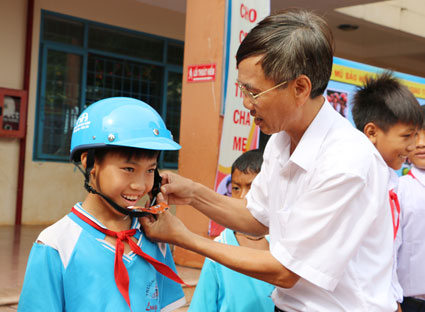 Ông Nguyễn Xuân Trạch, Chánh văn phòng Ban An toàn giao thông tỉnh trao mũ bảo hiểm cho học sinh nghèo của trường TH Long Tân