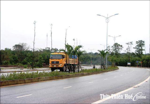 Tuyến đầu đường La Sơn - Nam Đông hoàn thành, được trồng cây xanh khang trang  Dự án (DA) đường La Sơn- Nam Đông có tổng chiều dài toàn tuyến hơn 38km, điểm đầu km0+00 giao với Quốc lộ 1A tại ngã ba La Sơn thuộc xã Lộc Sơn (Phú Lộc), điểm cuối km38+746,67 thuộc xã Thượng Quảng (Nam Đông) với tổng mức đầu tư trên 800 tỷ đồng.  Giai đoạn 1 của DA đã hoàn thành với việc xây dựng mới 7 cầu trên tuyến, xử lý 2 đoạn cua ở đèo La Hy. Giai đoạn 2 đang triển khai thi công với 4 gói thầu trên toàn tuyến. Ghi nhận ngay từ điểm đầu tuyến đường này, đến nay mọi công việc đã hoàn thành.  Ông Phạm Luyến, Giám đốc DNTN Xí nghiệp Lâm nghiệp Long Phụng cho biết, đơn vị đảm nhận thi công 4 km đầu tiên tiếp nối với Quốc lộ 1A. Trước đây vừa thi công, vừa khai thác tuyến nên gặp một số khó khăn do lượng phương tiện lưu thông đông, nền đường chưa được thảm nhựa, lầy lội. Đến nay mọi hạng mục đã thi công xong. Từ khi đưa vào sử dụng, giao thông thuận lợi, kết cấu  hạ tầng đồng bộ, góp phần vào sự phát triển khu công nghiệp La Sơn.  Trên địa bàn Hương Phú, Khe Tre (Nam Đông), hiện nay các đơn vị thi công đang thực hiện các gói thầu 17, 18, 29, 36. Ghi nhận tại công trường Khe Tre, những ngày nắng ráo, đơn vị thi công đang huy động máy móc, nhân lực, thi công một số hạng mục cuối cùng.  Tuyến La Sơn- Nam Đông đoạn qua thị trấn Khe Tre thuộc gói thầu 29- từ km21 + 949- km25 +766, trước đây còn nhếch nhác, bùn đất ngập ngụa, ảnh hưởng đến cuộc sống hàng trăm hộ dân, nay đã “nên hình hài” với con đường thảm nhựa rộng thênh thang. Đơn vị thi công đang triển khai một số hạng mục thuộc phần vỉa hè, lề đường, cây xanh và điện chiếu sáng. Những hộ dân hai bên đường cũng đã chỉnh trang nhà cửa, tạo nên diện mạo khang trang.  Tuy nhiên, tại gói thầu phần thuộc cầu Phú Mậu đến nay vẫn chưa thảm mặt cầu, một số điểm còn cấp phối đá dăm gồ ghề, gây khó khăn cho nhiều phương tiện qua lại, ảnh hưởng đời sống người dân ở khu vực này.  Tại gói thầu số 18- đoạn đường tránh Nam Đông dẫn lên cầu Hương Hòa hiện nay còn “vướng” công tác giải phóng mặt bằng do 4 hộ dân chưa đạt được thỏa thuận đền bù.  Ông Lê Văn Hoa, Giám đốc Công ty CP Thành Đạt- đơn vị đảm nhận gói thầu này cho biết, gói thấu số 18 với tổng giá trị 98 tỷ đồng, đến nay đã thi công hoàn thành được 70 tỷ đồng. “Cầu Hương Hòa có giá trị thi công 23 tỷ đồng, đến nay cơ bản đã xong. Hạng mục này chậm là do trong quá trình thi công gặp sự cố hang cát tơ, búa đập bị rơi xuống kẹt lại trong hang nên phải mất thời gian xử lý”, ông Hoa cho biết.  Tại gói thầu số 17 cơ bản đã xong, chỉ còn khoảng 200m mặt đường chưa thảm nhựa được đoạn qua địa bàn xã Hương Hữu do còn vướng mặt bằng của 10 hộ dân chưa thỏa thuận được đền bù. Hiện nay, Trung tâm Phát triển quỹ đất huyện Nam Đông đang phối hợp với các cơ quan chức năng tiến hành vận động, giải thích cho người dân tháo gỡ “điểm nghẽn” này.  Ông Nguyễn Văn Cường, Phó Giám đốc Ban Đầu tư và Xây dựng giao thông (UBND tỉnh)- đơn vị chủ đầu tư DA đường La Sơn - Nam Đông cho biết: “Các hộ dân bị ảnh hưởng nứt nhà trong quá trình thi công chủ yếu thuộc gói thầu 29- đoạn qua thị trấn Khe Tre. Hiện nay, có 52 nhà dân đã được thuê đơn vị kiểm định độc lập và sẽ được chi trả đền bù trong thời gian tới”.  Ông Cường cho biết thêm, tính đến thời điểm hiện tại, trong 807 tỷ đồng được phê duyệt, Trung ương đã phân bổ được 803 tỷ đồng, các gói thầu thi công đều cơ bản hoàn thành từ 80-90% khối lượng công việc. Ngoài một số điểm đang vướng công tác giải phóng mặt bằng (đến nay tổng số tiền đền bù cho các hộ dân bị ảnh hưởng, di dời là 132 tỷ đồng), nguyên nhân một số hạng mục chậm tiến độ là do thời tiết Nam Đông buổi chiều thường mưa kéo dài cho đến tối nên việc thi công gặp một số khó khăn.  “Chủ đầu tư thường xuyên đôn đốc, nhắc nhở các đơn vị thi công ngoài đảm bảo an toàn giao thông, vệ sinh môi trường, hạn chế thấp nhất ảnh hưởng đến cuộc sống người dân, còn yêu cầu các nhà thầu thi công tận dụng thời tiết thuận lợi, huy động nhân, vật lực thi công, đảm bảo tiến độ, sớm đưa công trình về đích”, ông Cường nói.